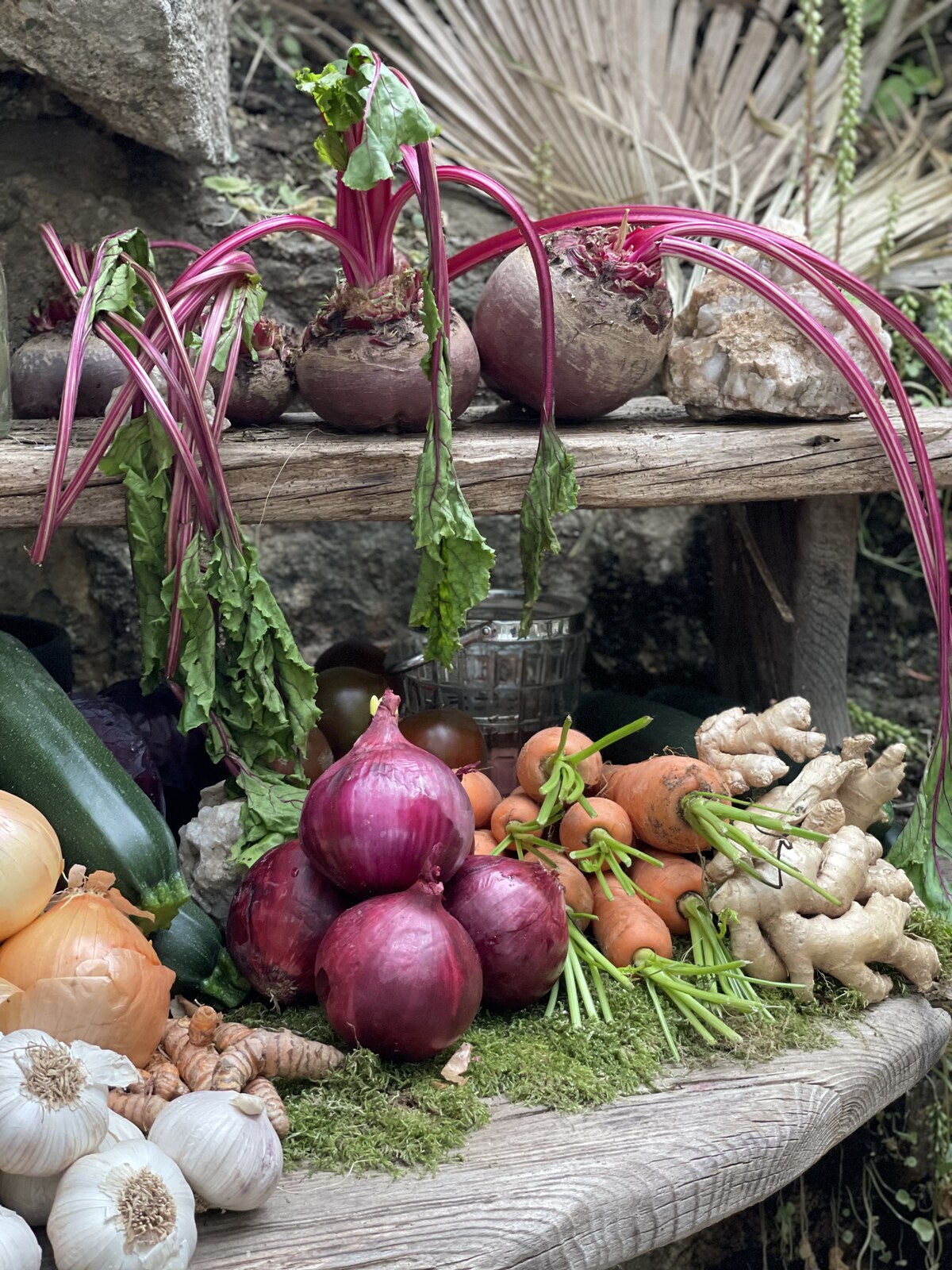 Fresh seasonal vegetables and roots arranged on a rustic outdoor shelf by Skarabo Life