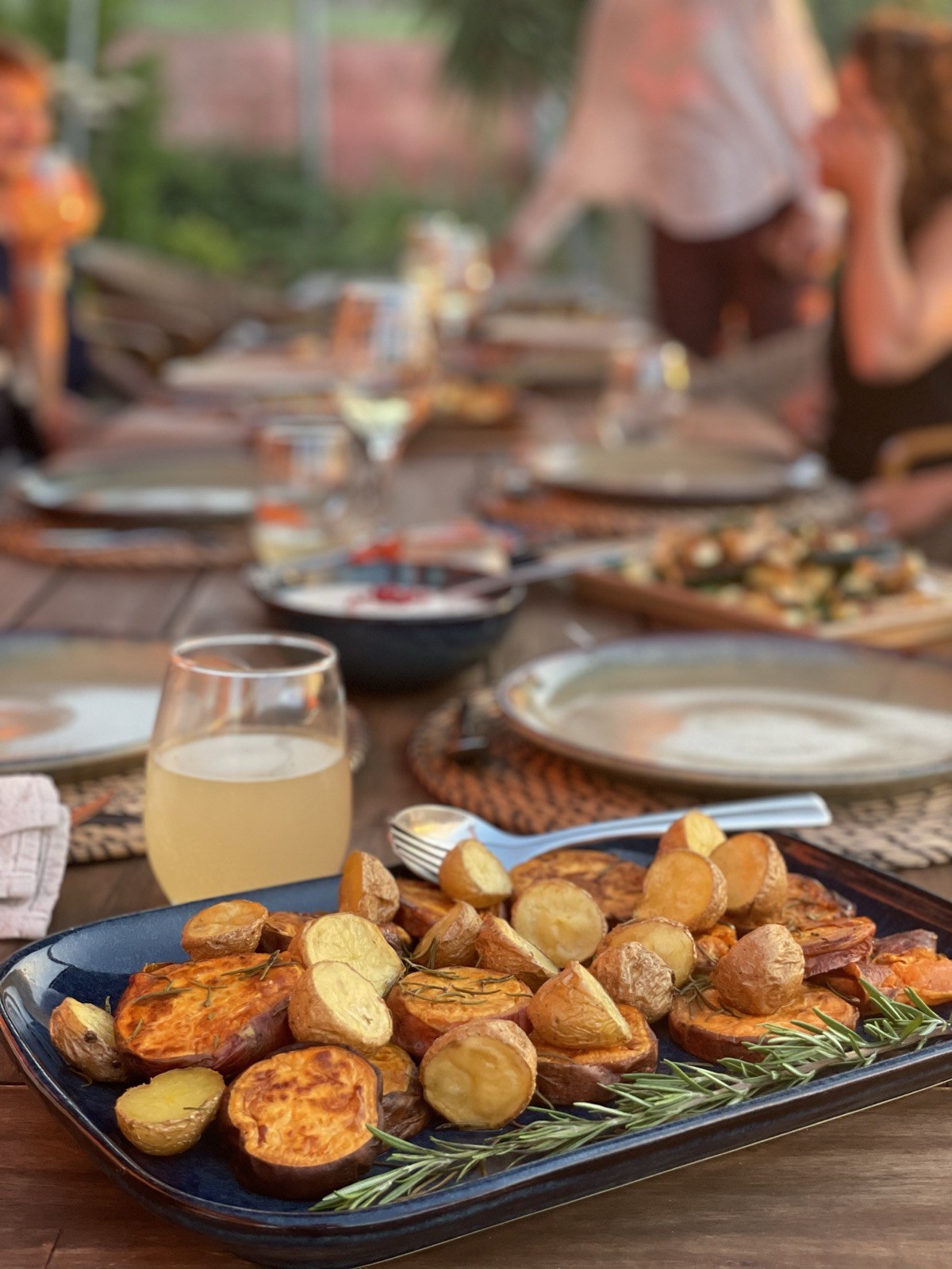Roasted potatoes and sweet potatoes with rosemary at a golden-hour outdoor retreat table